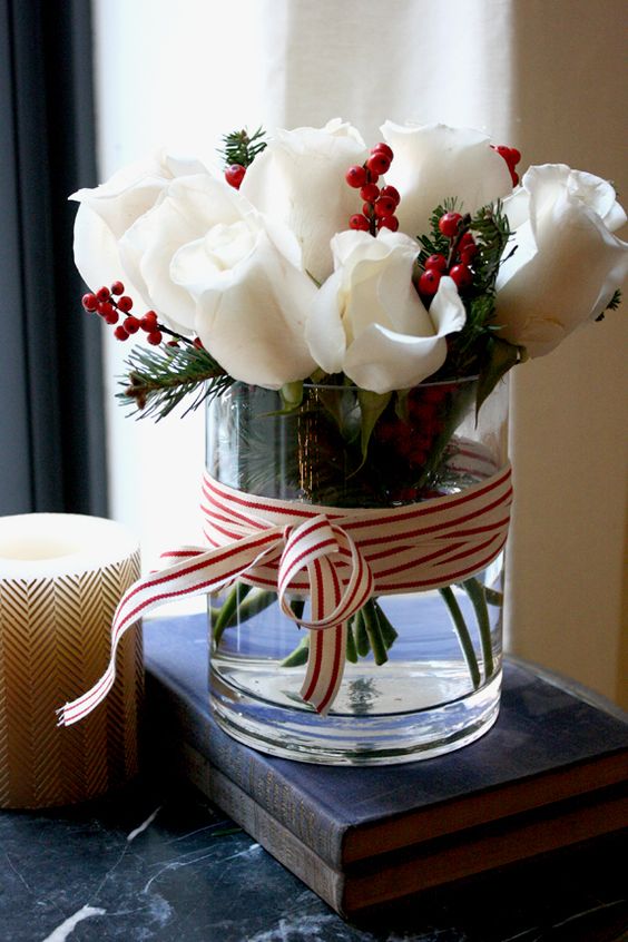 White roses, with winter berries in a glass vase