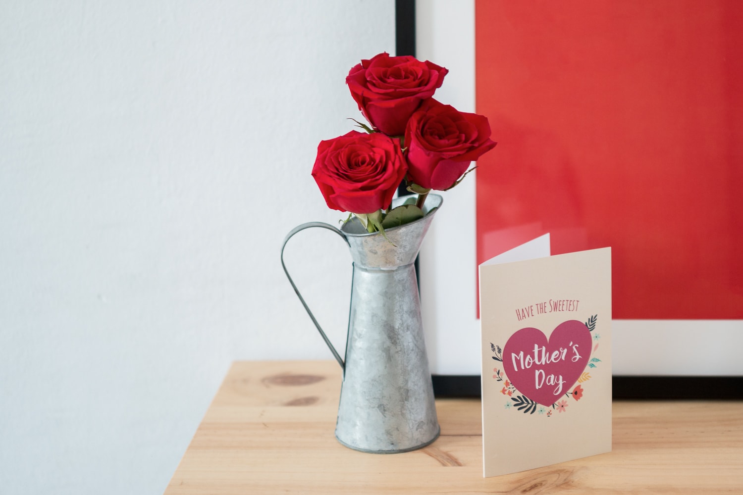 Red roses with mother's day card in a watering can vase