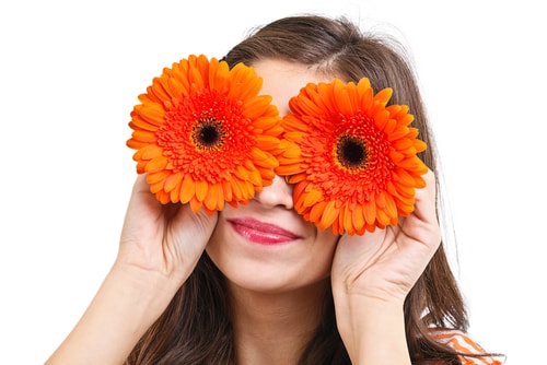 Glückliches Mädchen mit orangen Gerbera über den Augen