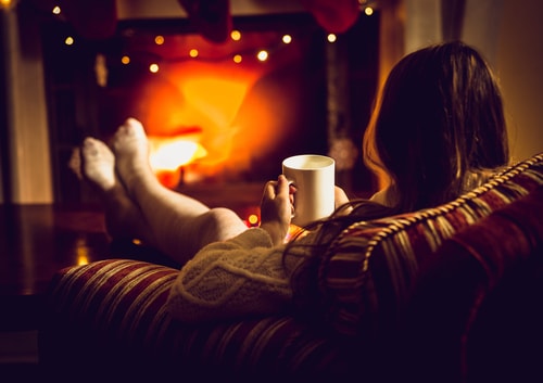 woman relaxing by fire with hot drink
