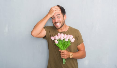 man holding flowers with look of horror