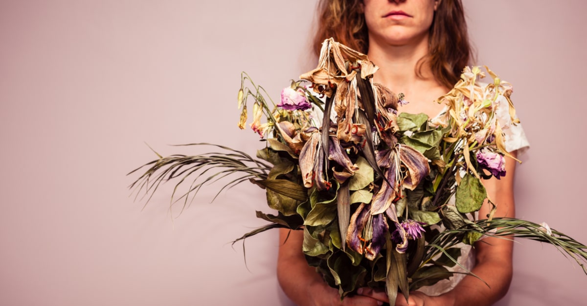 Unhappy woman holding dead flowers