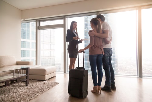 couple with suitcases in empty apartment
