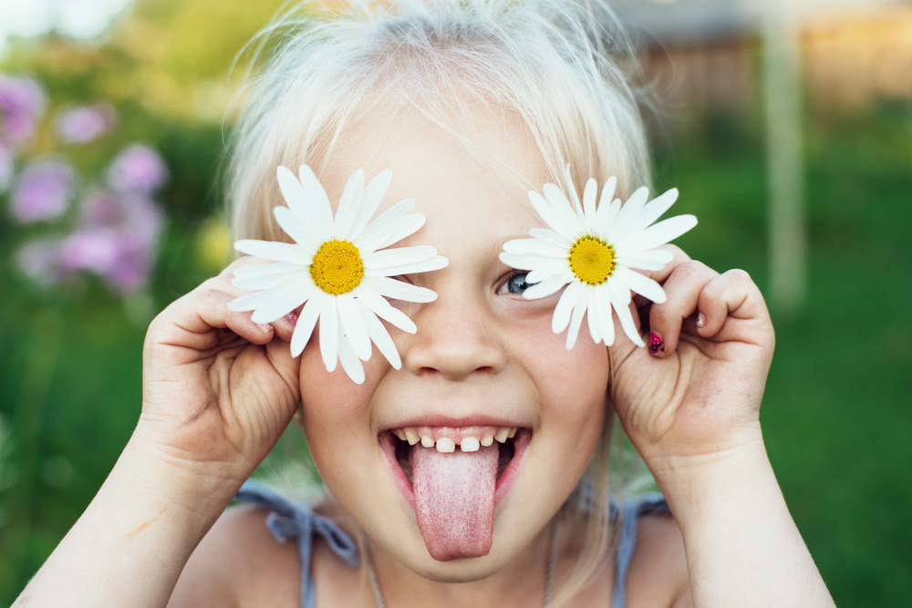 petite fille avec des fleurs et tirant la langue