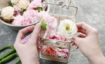 fleuriste mettant des fleurs dans une cage de décoration