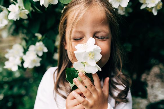 petite fille sentant une fleur