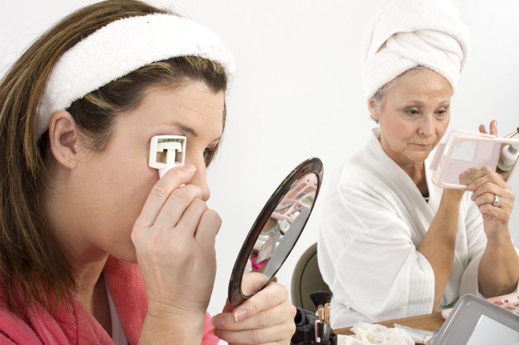 Two woman doing facials and make-overs. Focus on woman on left curling eyelashes.