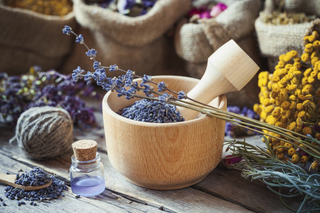 Healing herbs in hessian bags, wooden mortar with lavender flowers, bottles with tincture, herbal medicine. Selective focus.